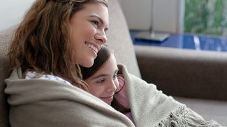 Une mère et son enfant blottis sous une couverture sur un canapé